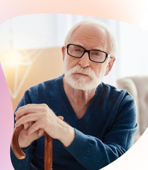 Older man sitting thoughtfully at home, holding a walking cane